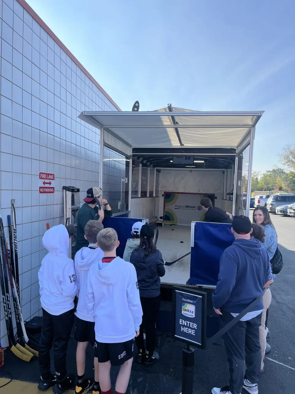Kids line up at the RapidShot Mobile trailer at an outdoor event